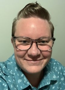 Dani wearing a green shirt with white patterns, smiling at the camera